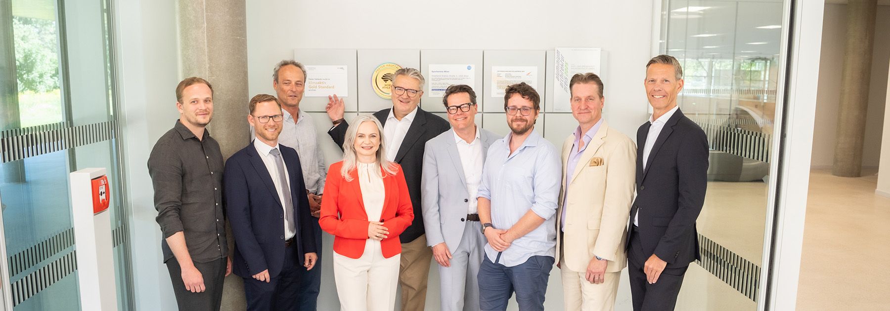 8 Herren und eine Dame stehen vor der klimaaktiv Gold Plakette