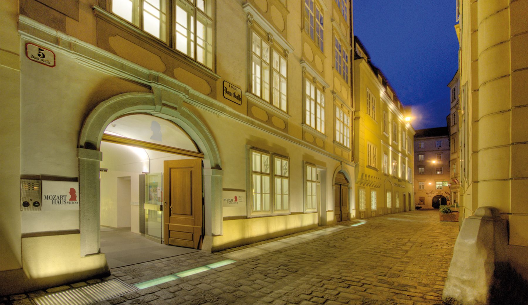 Zu sehen ist die Außenansicht des Mozarthaus Vienna bei Nacht - stimmungsvoll beleuchtet.