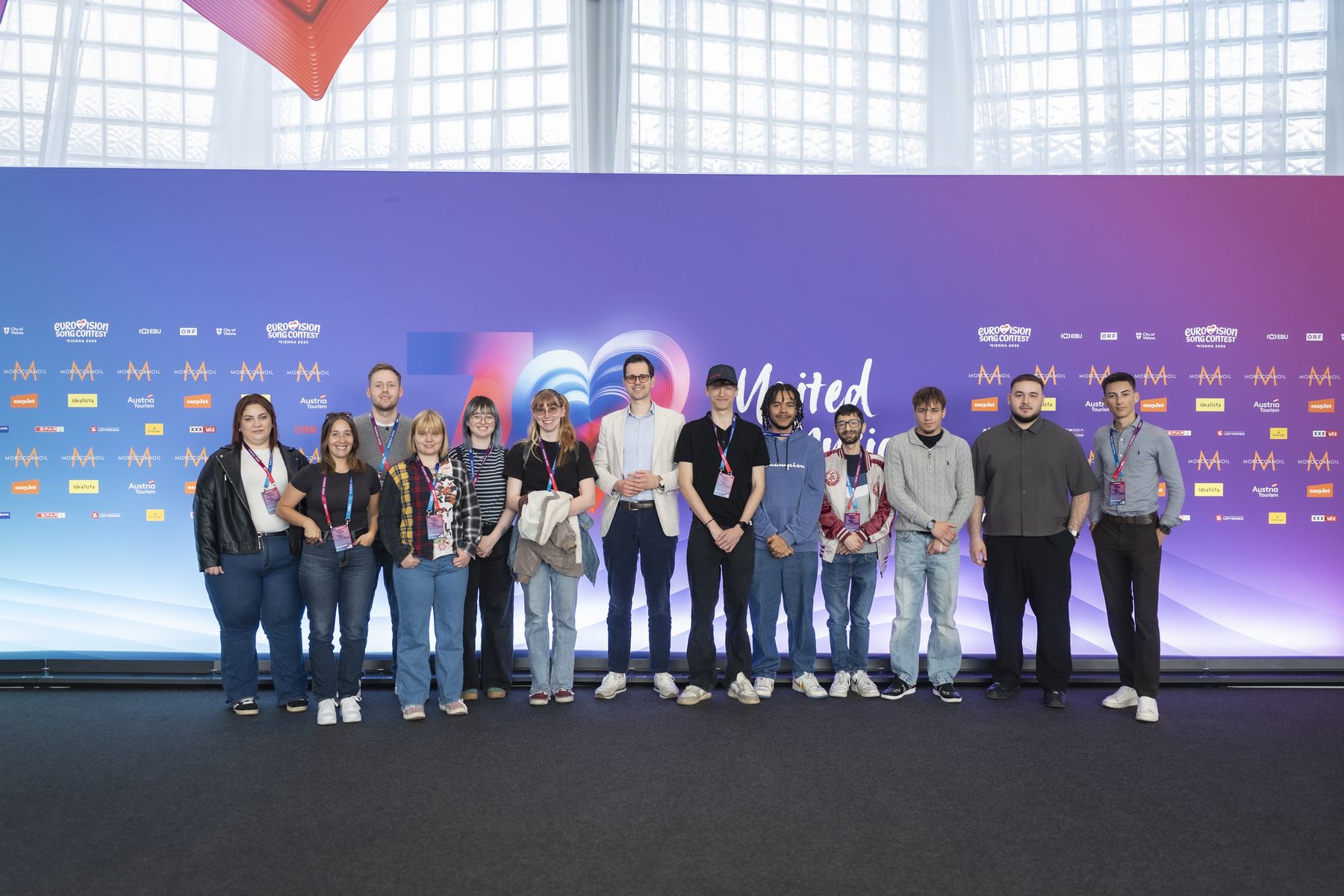 eine Gruppe junger Menschen vor einer ESC-Kulisse