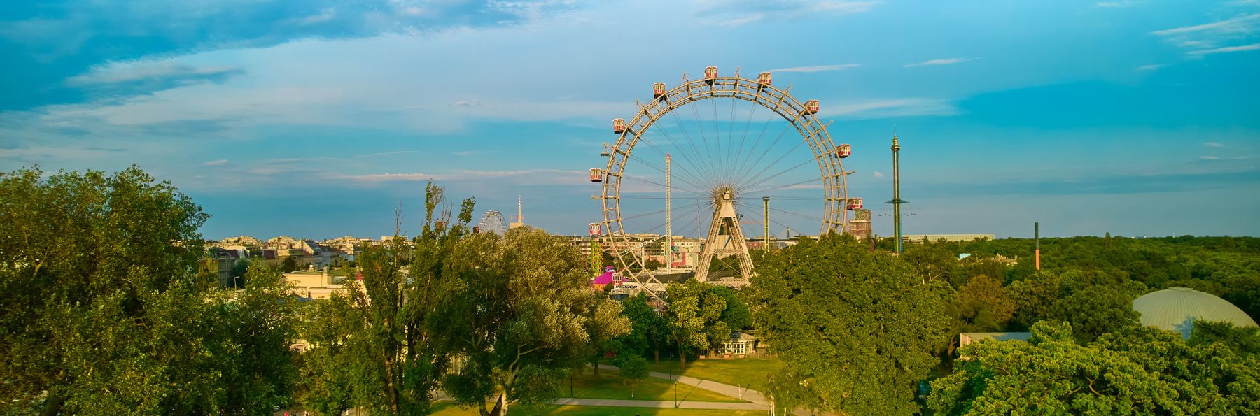 Panoramablick über den Prater in Wien mit dem Riesenrad und zahlreichen Bäumen.