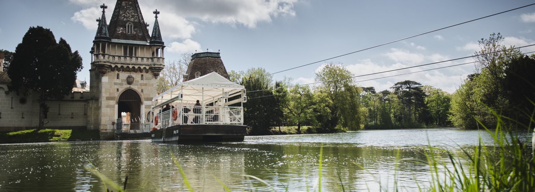 Eine Fähre fährt zur Franzensburg auf dem See.