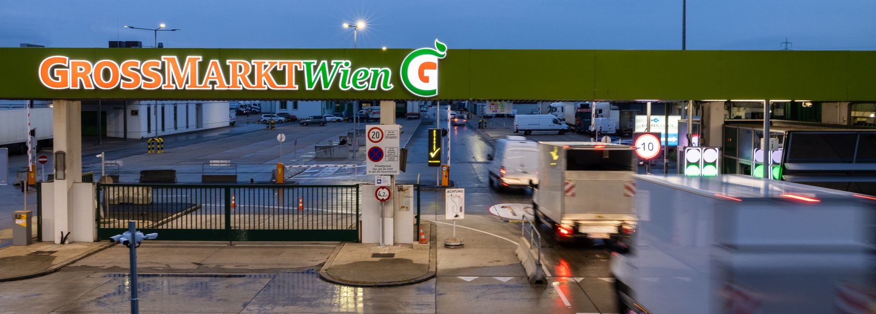 Einfahrt des Großmarkt Wien vor einem dämmrigen Himmel.