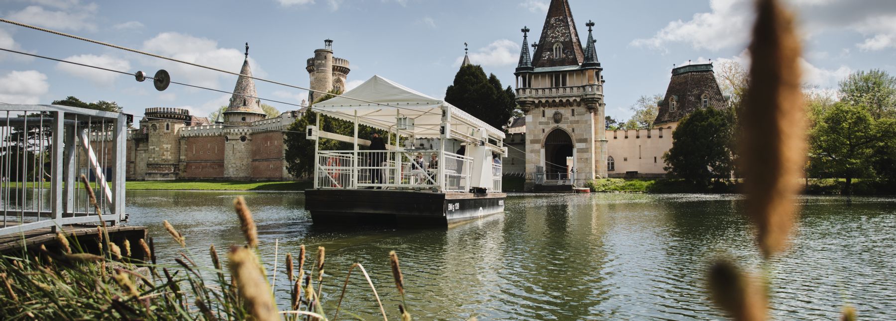 Eine Fähre fährt zur Franzensburg auf dem See.