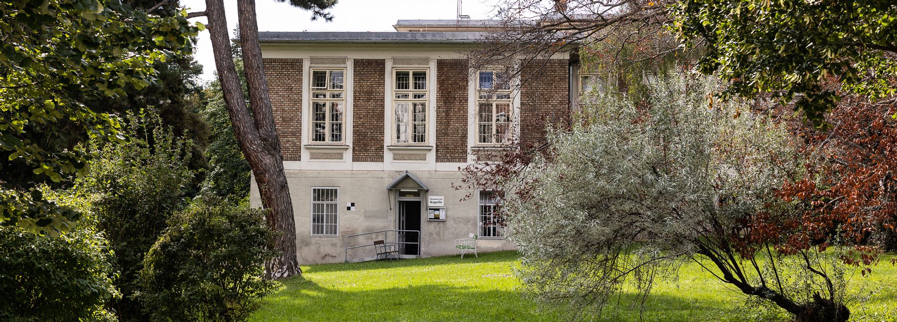 Backsteingebäude am Otto-Wagner-Areal, umgeben von Wiese und Bäumen.