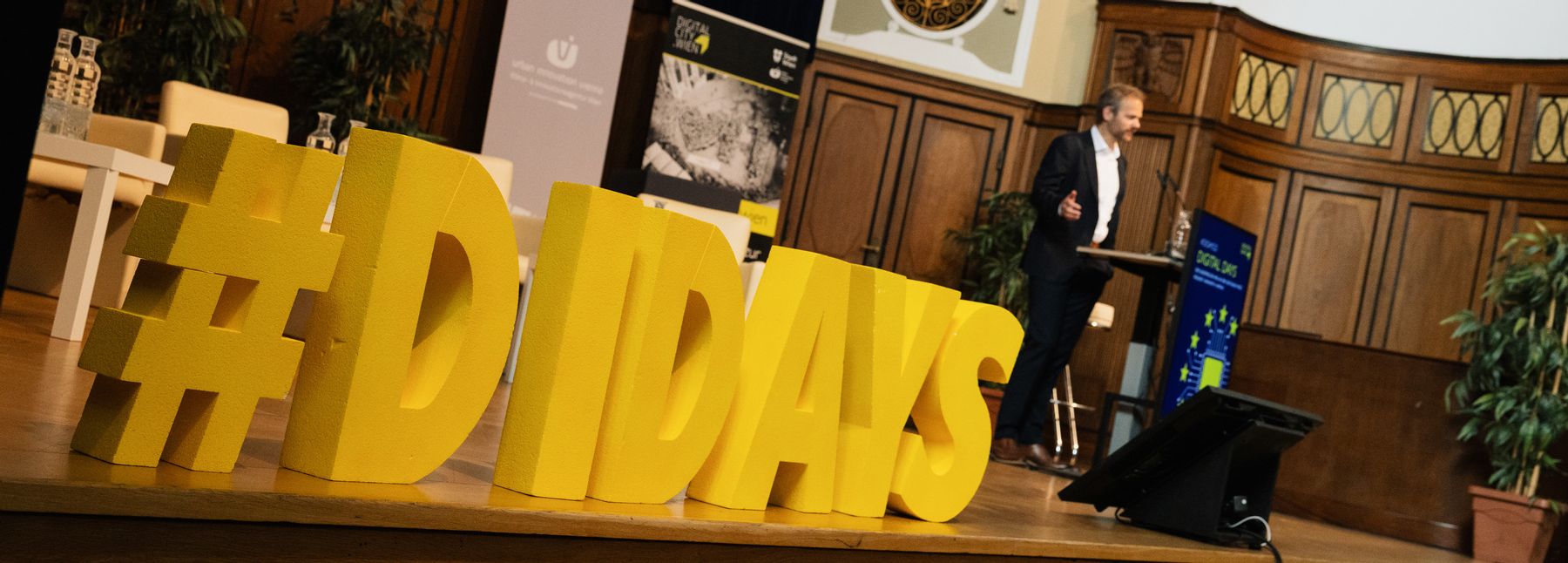 Auf einer hölzernen Bühne steht groß der gelbe Schriftzug „#DIDAYS“.