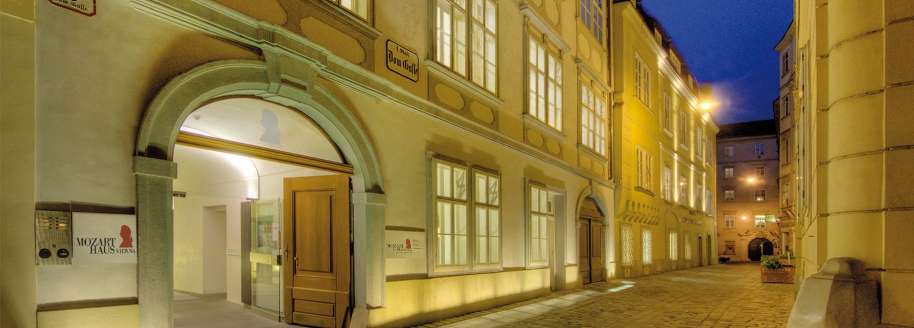 Zu sehen ist die Außenansicht des Mozarthaus Vienna bei Nacht - stimmungsvoll beleuchtet.