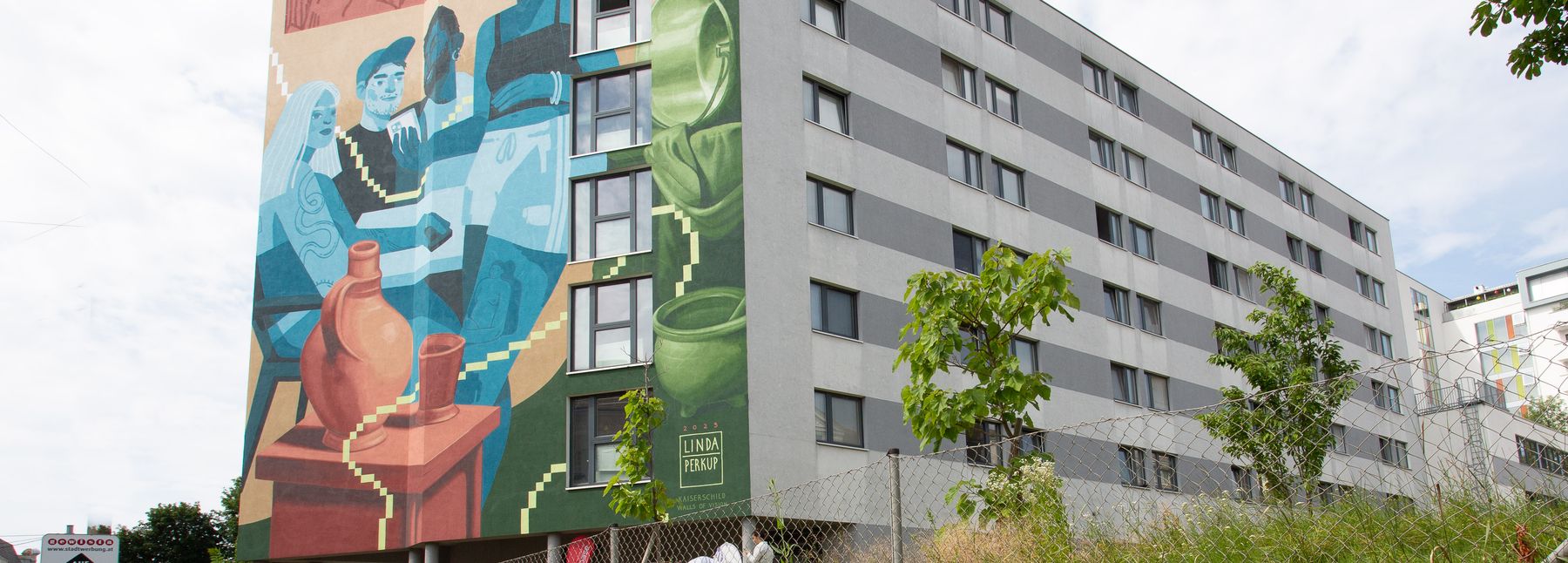 Außenansicht der Viennabase19, ein kastenförmiges Gebäude mit einer bunten Graffiti-Wand an der Seite.