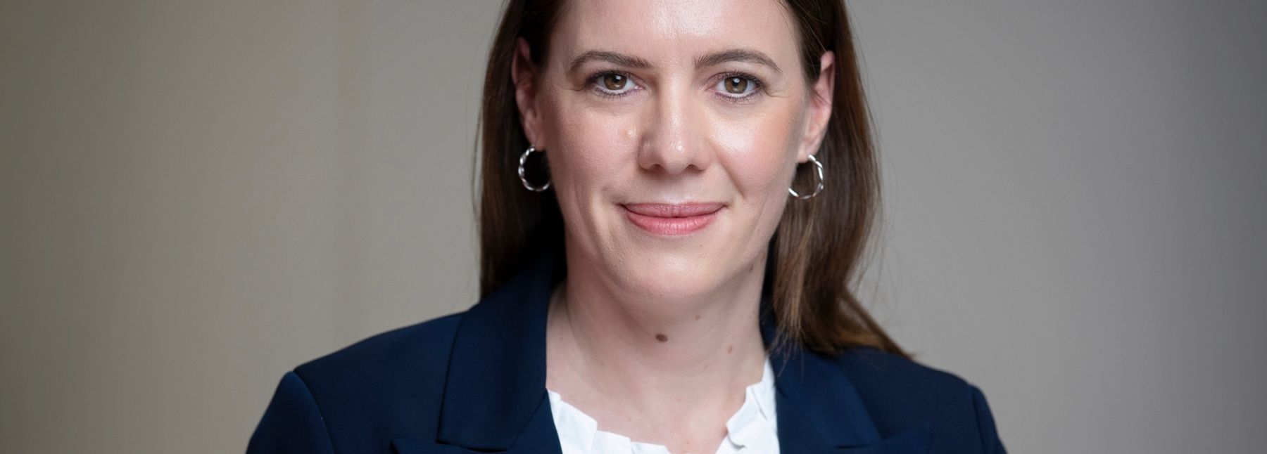 Eine Frau in Business-Kleidung blickt in die Kamera