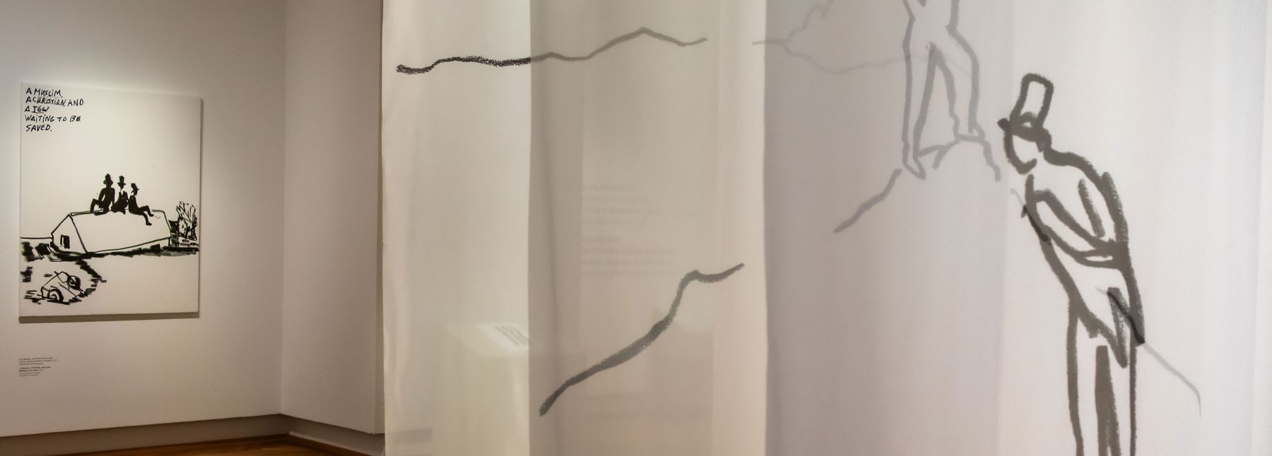 In der Ausstellungsansicht zu sehen sind die drei Hauptfiguren von Eran Shakine auf einem gezeichneten Berg