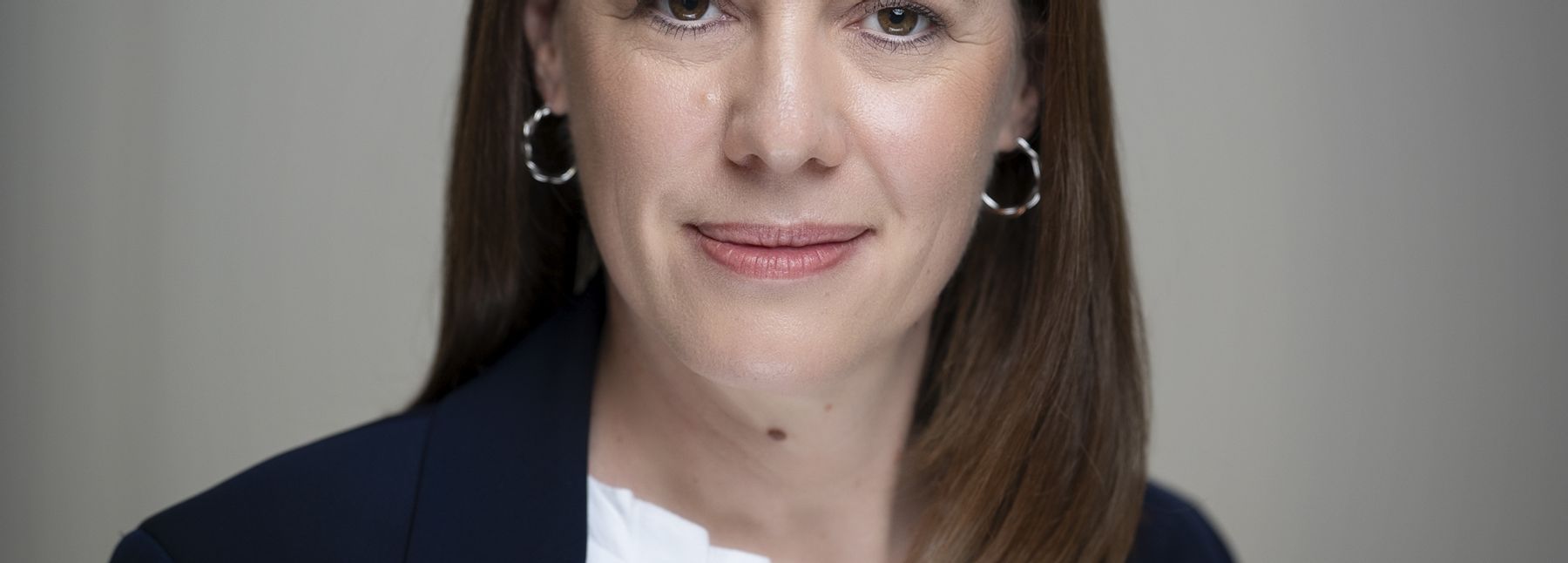 Eine Frau in Business-Kleidung blickt in die Kamera