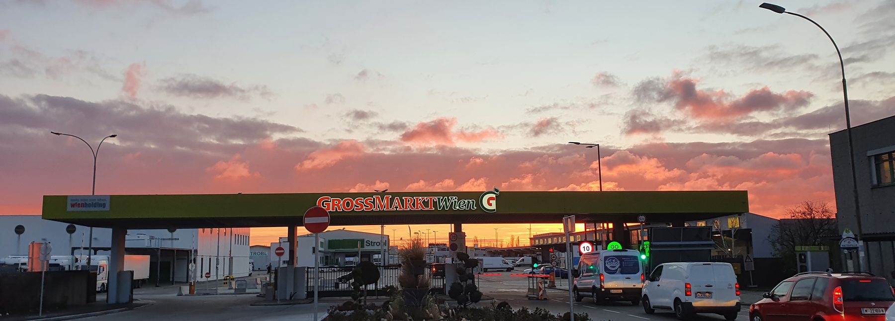 Einfahrt des Großmarkt Wien mit leicht rosa gefärbtem Himmel im Hintergrund.