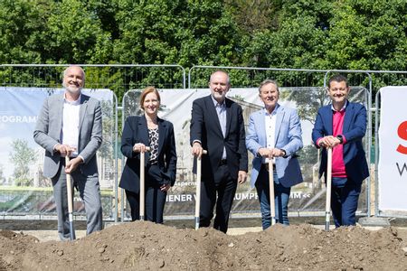 Vier Herren und eine Dame stehen mit Schaufeln vor einem Erdhügel