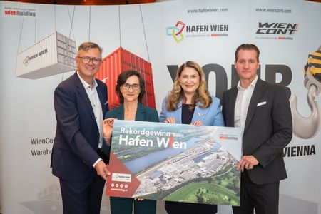 Zwei Damen und zwei Herren halten eine Tafel, auf dem eine Luftaufnahme des Hafen Wien zu sehen ist.
