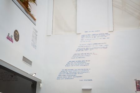 Ein Wandbild das einen Text über Gott von Karl Wolfskehl darstellt.