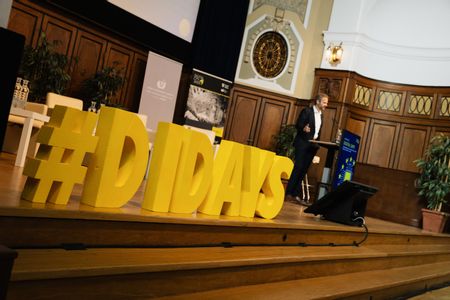 Auf einer hölzernen Bühne steht groß der gelbe Schriftzug „#DIDAYS“.