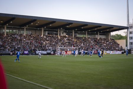 Ein Fußballstadion mit Spielern auf dem Feld und Fans auf den Tribünen