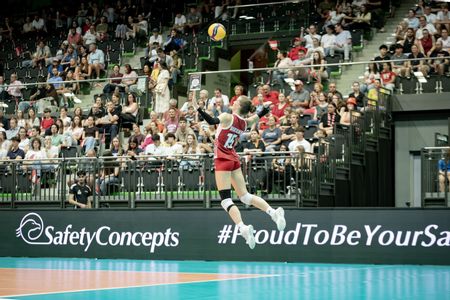 Eine Volleyballspielerin in einer Sporthalle vor Publikum 