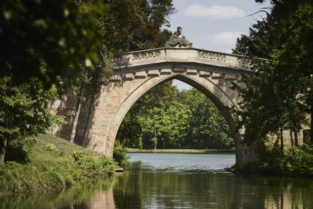 Eine Brücke aus Stein über einen See im Schlosspark Laxenburg.