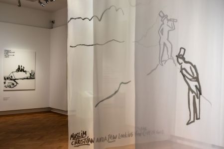 In der Ausstellungsansicht zu sehen sind die drei Hauptfiguren von Eran Shakine auf einem gezeichneten Berg