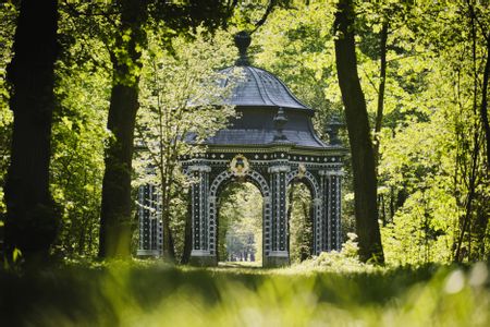 Der Pavillon im Schlosspark Laxenburg ist zwischen grünen Bäumen zu sehen.