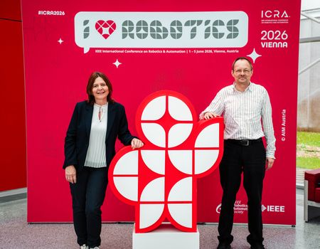 Eine Dame und ein Herr vor einem "I love Robotics" Plakat