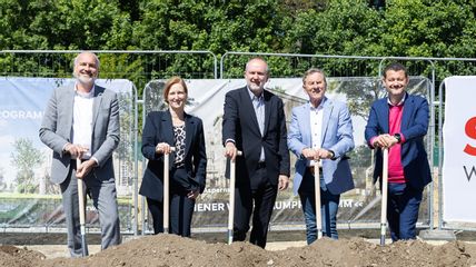 Vier Herren und eine Dame stehen mit Schaufeln vor einem Erdhügel