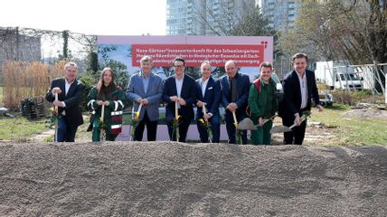 Menschen mit Schaufeln vor Sandhaufen