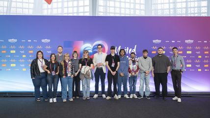 eine Gruppe junger Menschen vor einer ESC-Kulisse