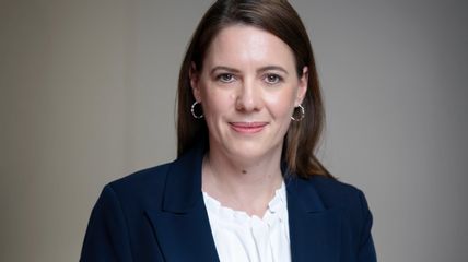 Eine Frau in Business-Kleidung blickt in die Kamera